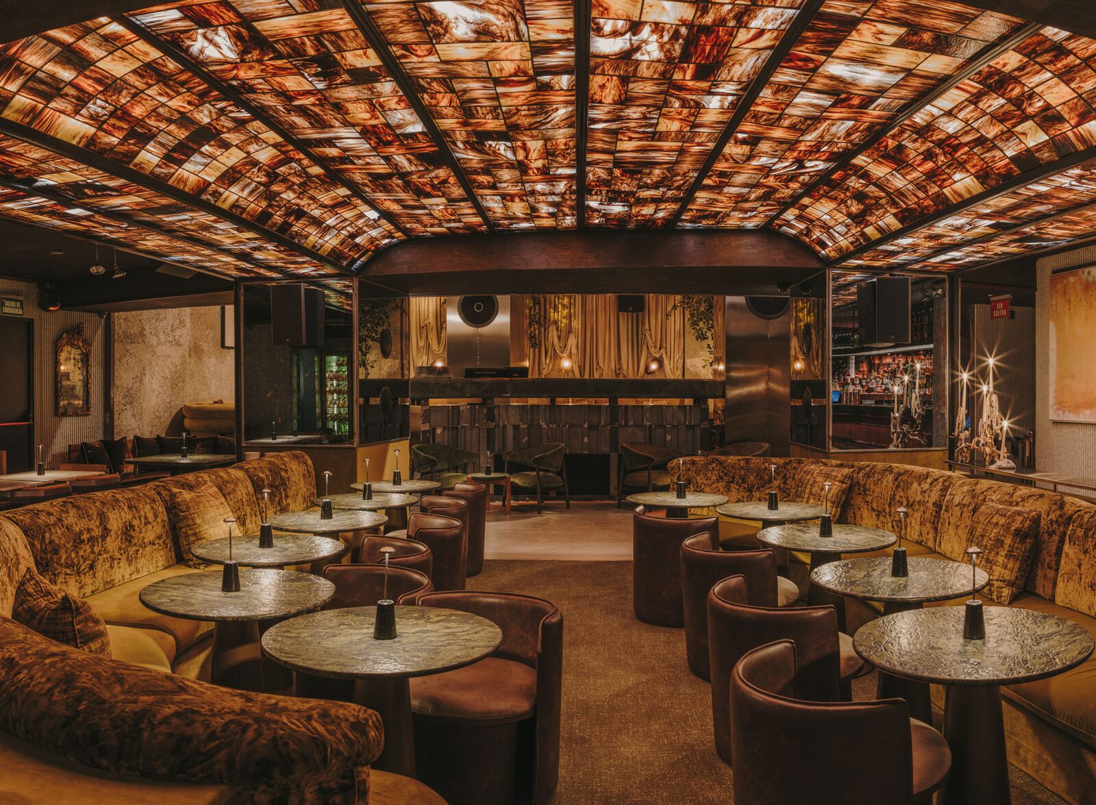 Sala secreta de 61 con techo de vidrio retroiluminado, sofás corridos de terciopelo y mesas de piedra