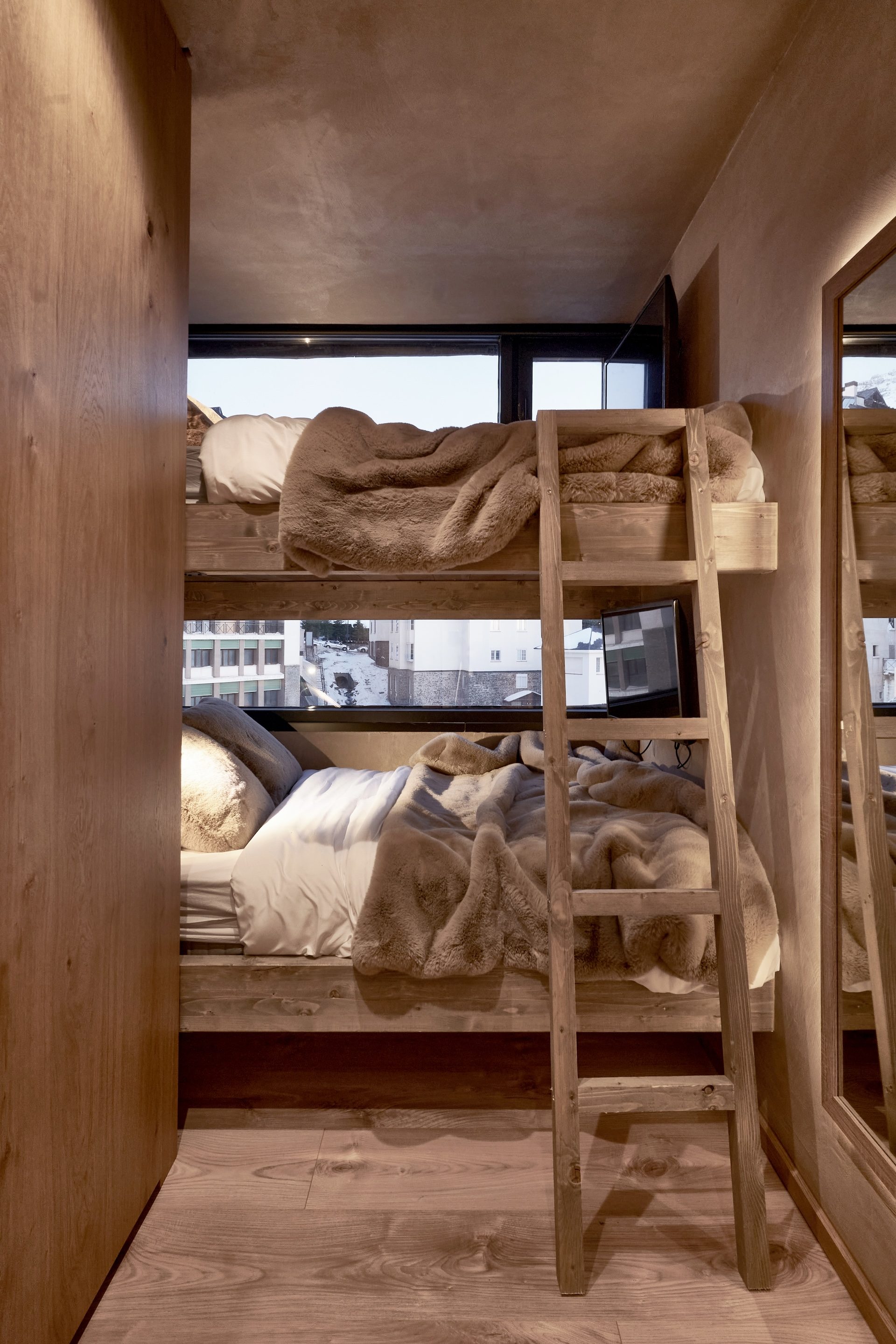 Dormitorio con literas de madera maciza, mantas de pelo y ventana alargada en el Ático Nevado