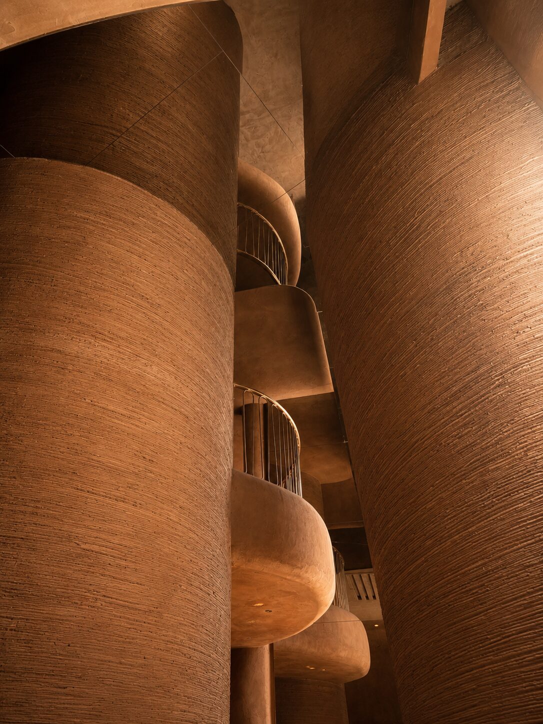 Detail of the terracotta-textured columns and curved balconies at Bro Club in Málaga
